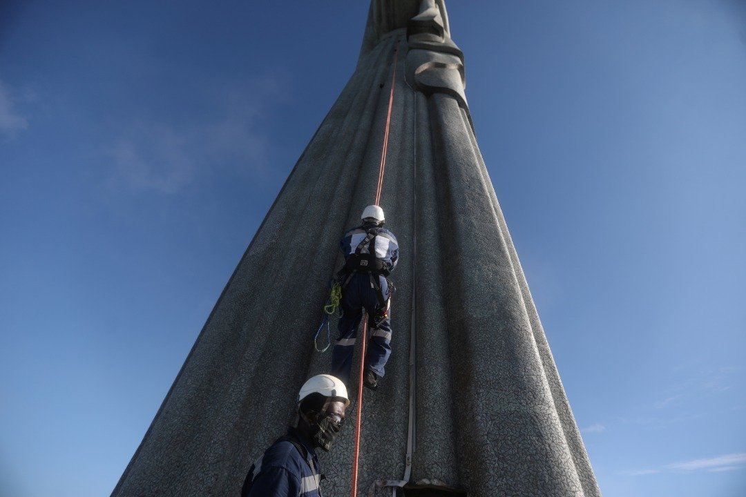 几名维修人员腰间挂著安全绳，缓缓爬上里约热内卢的耶稣像，以进行修复工作，迎接雕像建成90周年纪念。（图取自路透社）