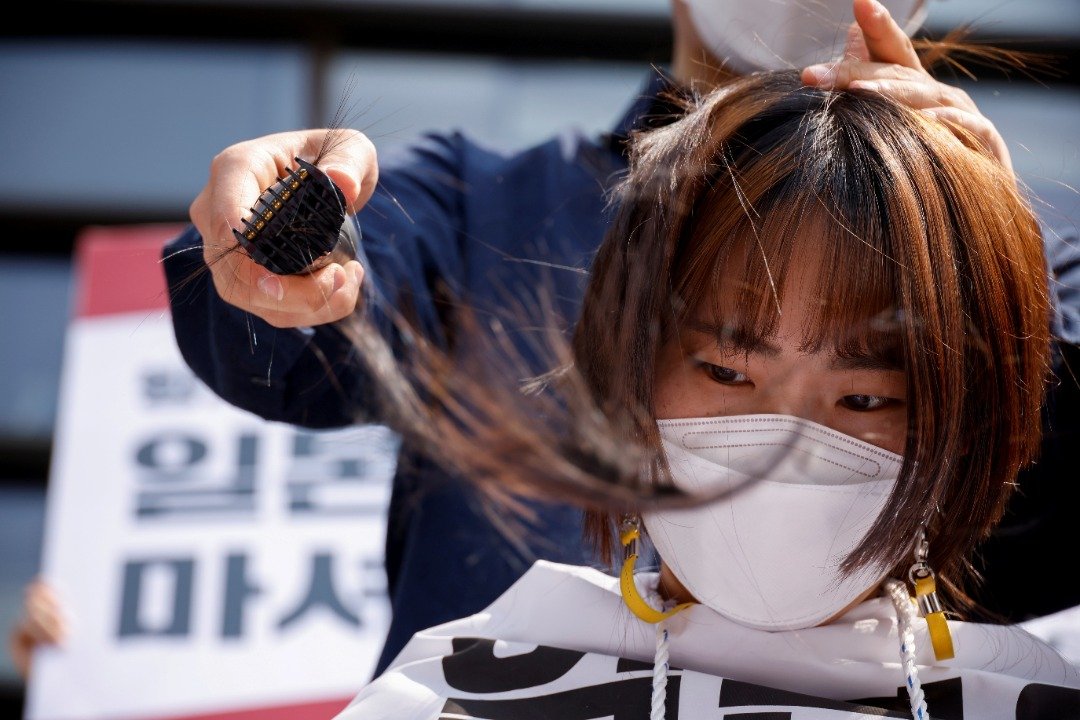 为抗议日本政府的决定，女大学生不惜剃下秀发。（图取自路透社）