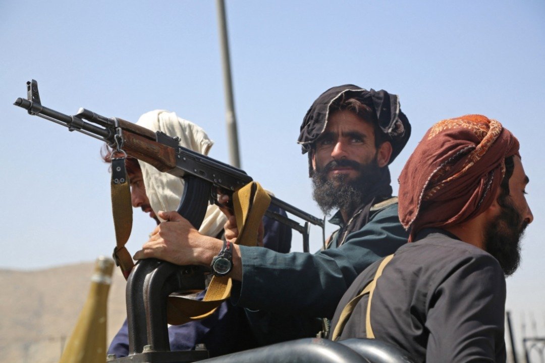 阿富汗武装组织塔利班战士周一于首都喀布尔，站在一辆车上站岗。（图取自法新社）
