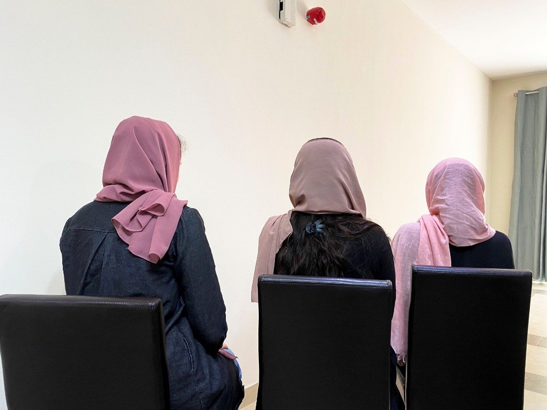 在卡塔尔多哈一个住宅区，3名逃离国家的阿富汗女大学生，为了人身安全考量对记者背对著镜头隐藏身分。（图取自路透社）