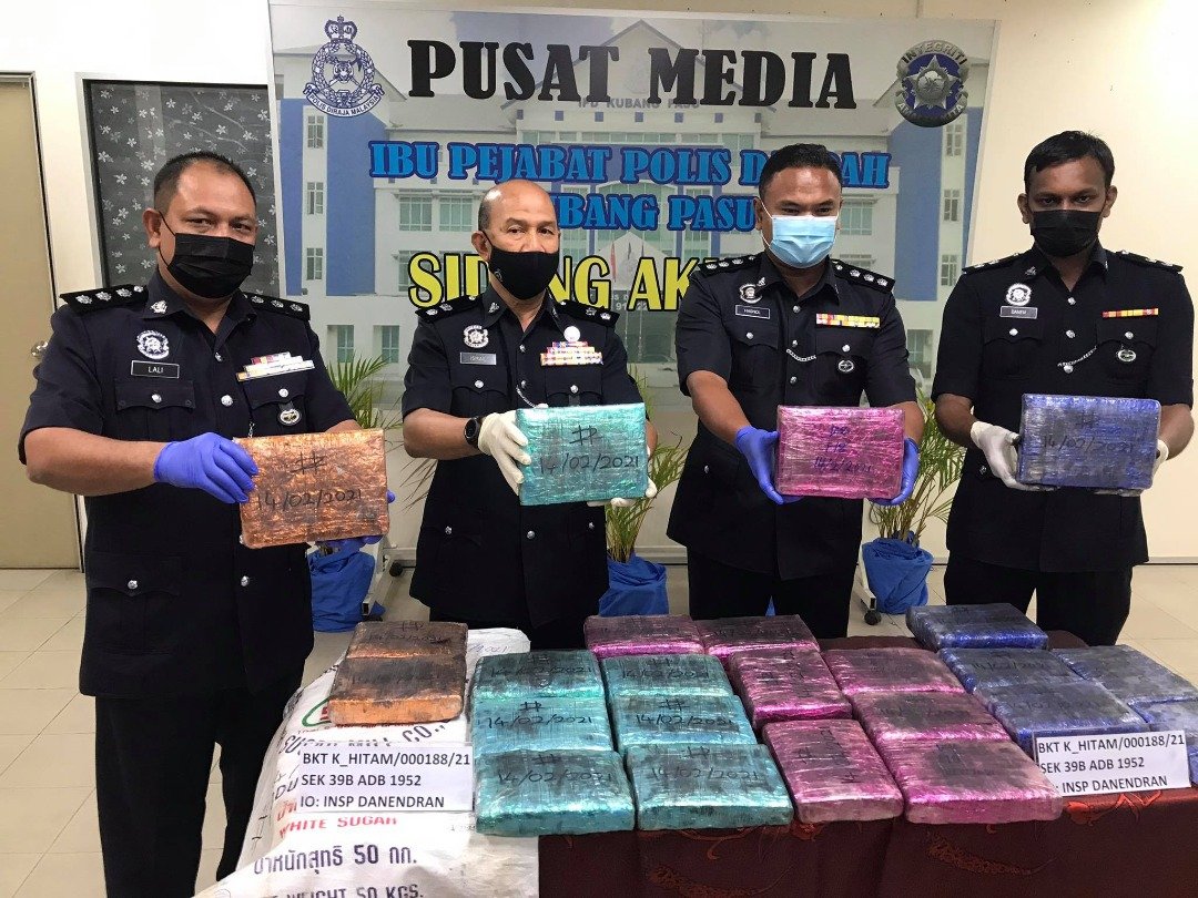莫哈末依斯迈（左2）展示警方起获包装成五颜六色的大麻砖。