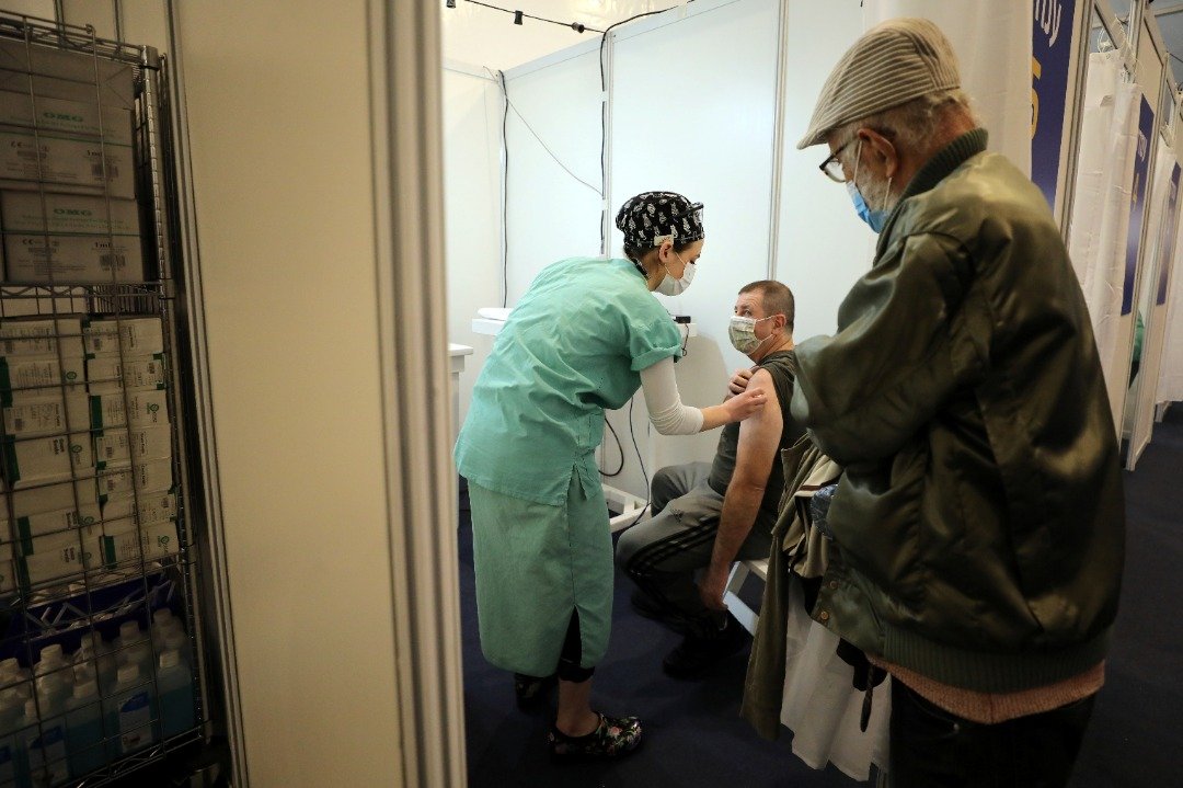 戴著口罩的医护人员于上周四在特拉维夫的拉宾广场疫苗接种中心内，为一名老年人施打新冠肺炎疫苗。（路透社）