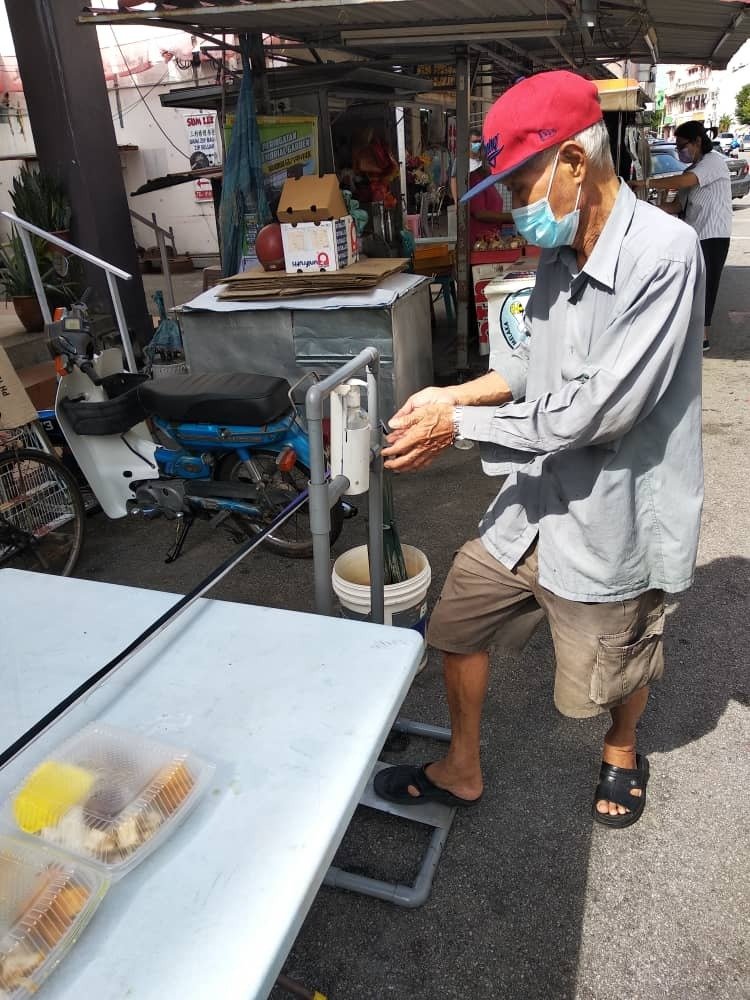 义工准备脚踏式消毒支架，让领取免费午餐的人士使用，预防病毒传播。