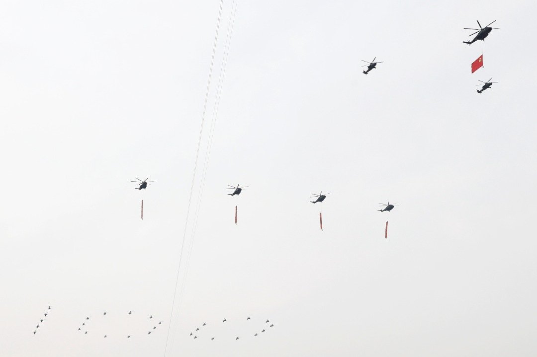 7架直升机悬挂党旗和四面巨幅标语，飞越天安门广场。（图取自路透社）
