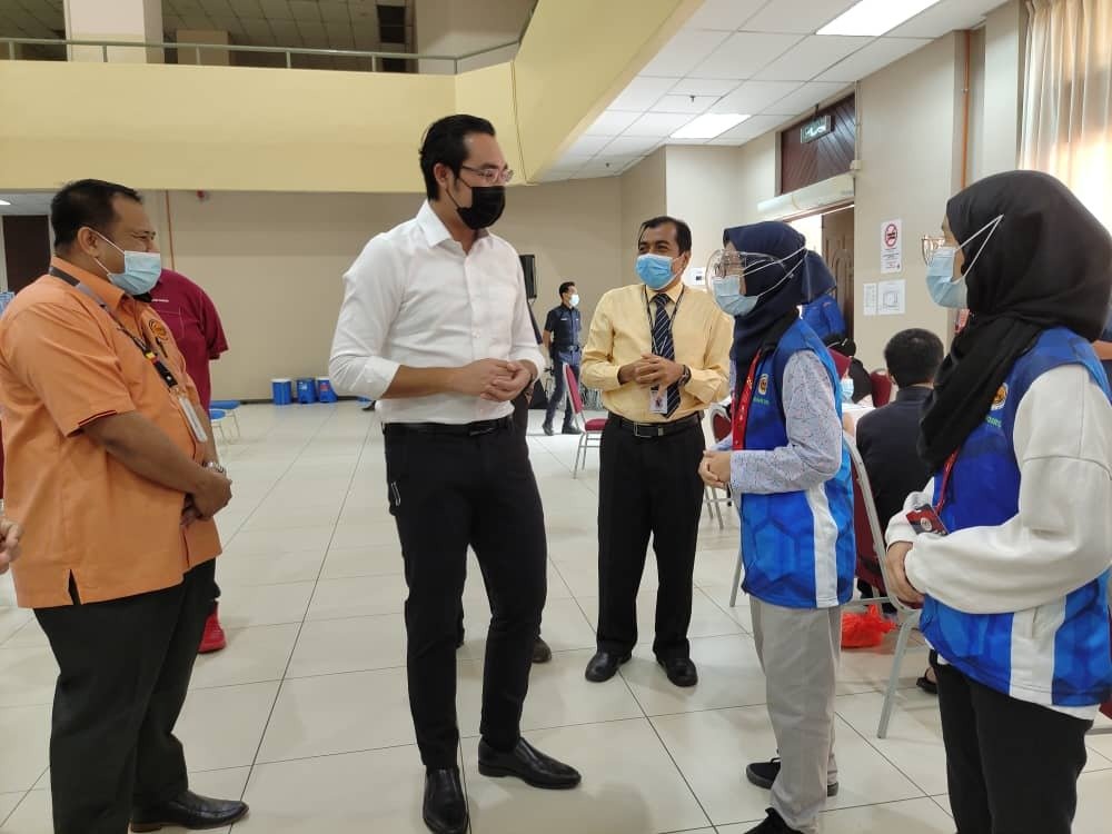旺阿末法依沙（左2）向志愿者了解他们在接种疫苗中心的工作范畴，且对于该中心的运作感到满意。