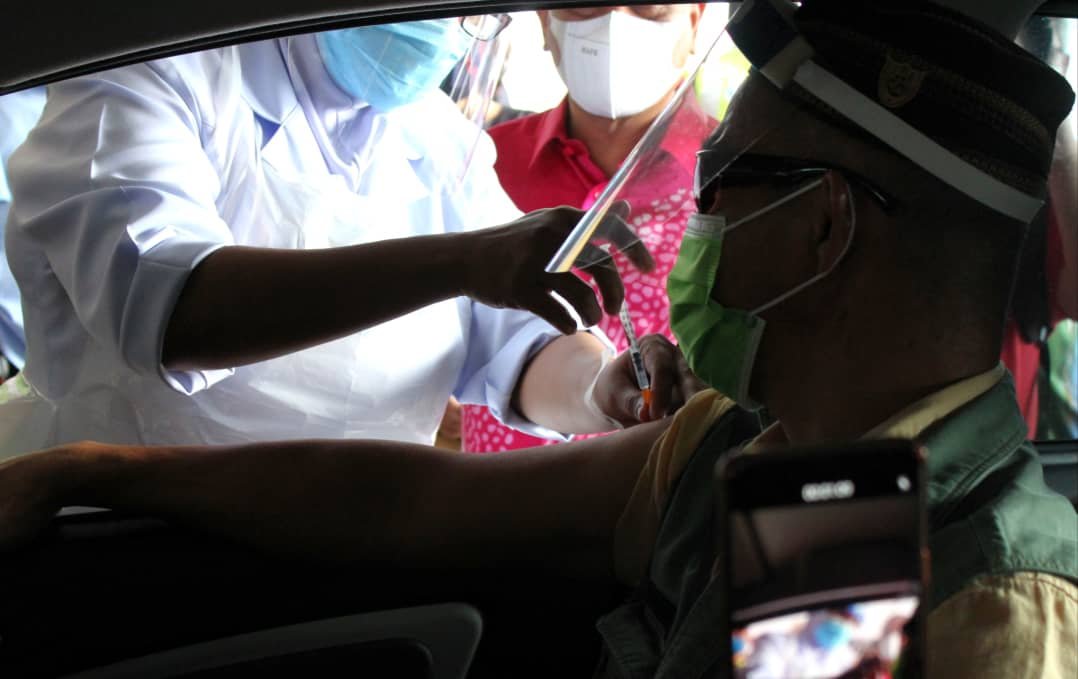 医护人员隔著一道车门，为民众接种疫苗。