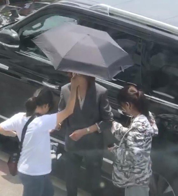一个助手为她撑伞。