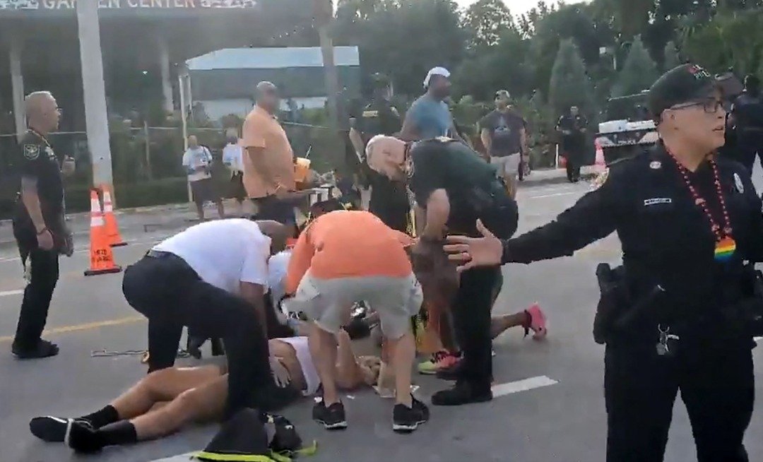 在皮卡车冲撞佛州的同志游行聚集人群后，警察和在场民众帮助被撞倒在地的的两个人。（图取自@pinto_spears/法新社）