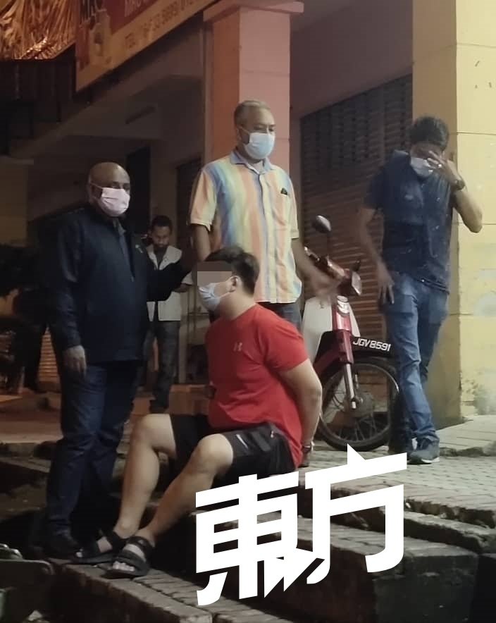 警方在现场逮捕一名华裔男子（坐者），准备带返警局协助调查。