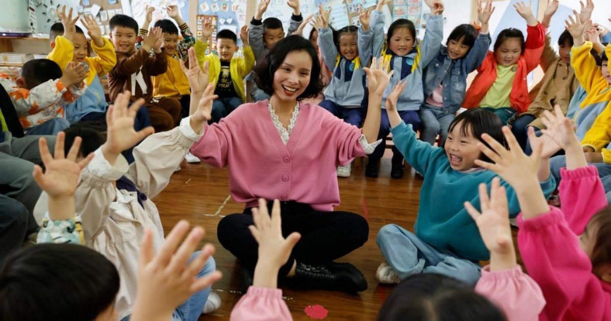 贵州省遵义市正安县机关幼儿园的老师带著孩子们一起做游戏。