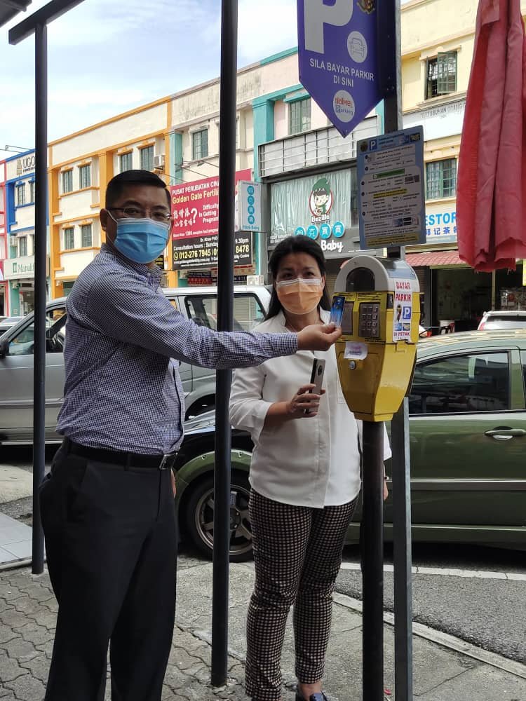 郑正成（左）及叶小瑂现场展示已被停用的停车费缴付机，为拥有充值卡地位民众制造不必要地位麻烦。