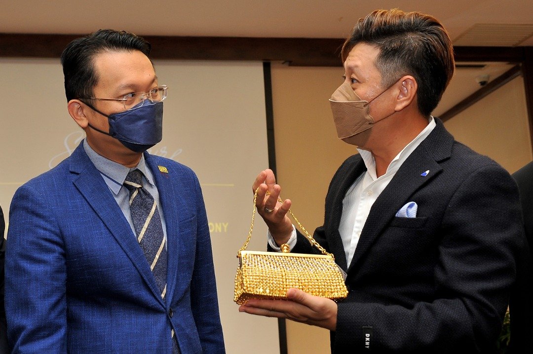 林泳煌（右）向杨顺兴（左）展示市值约30万令吉的“黄金包包”。