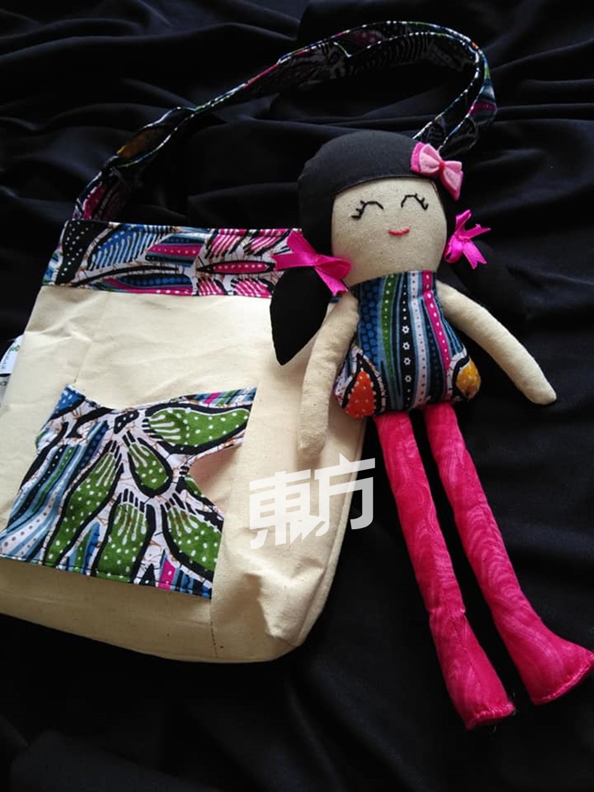 UmieAktif妈妈们的手缝作品不乏创意巧思。图中的手提袋外层饰有口袋，可以随意置放或取出布娃娃，为原本普通的袋子增添趣味。