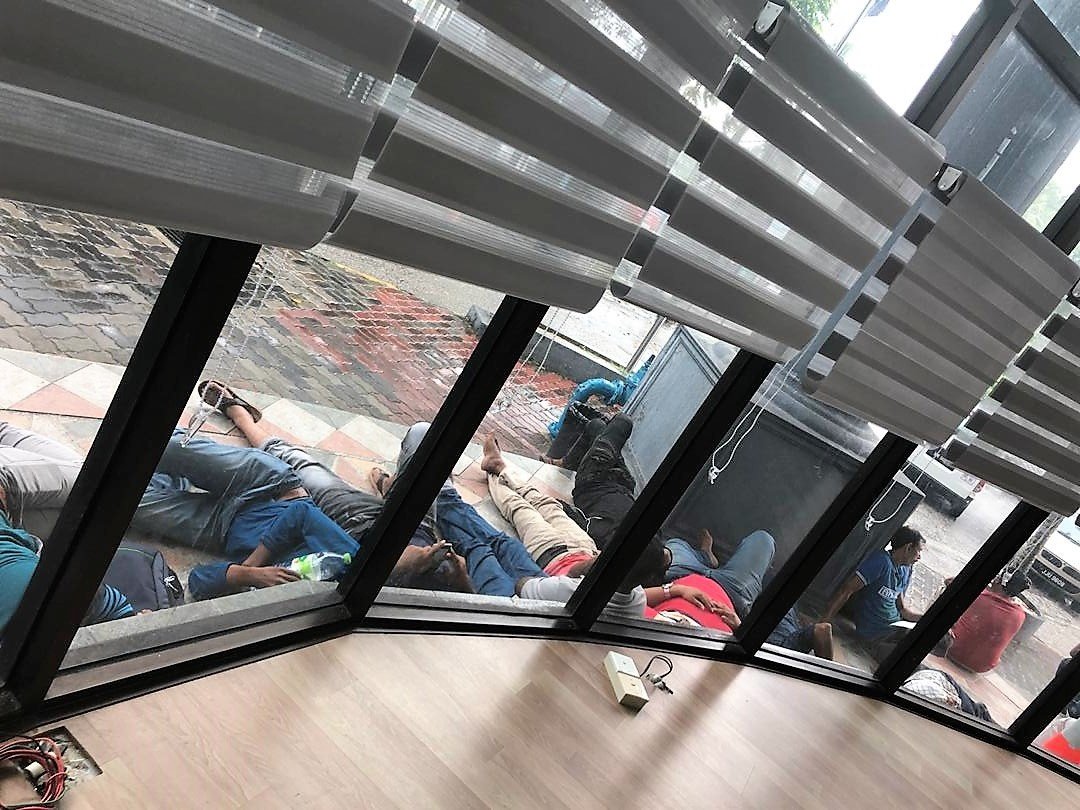 外劳群聚在新山TJB大厦外的五脚基，有者睡在五脚基处，阻碍租户及民众进出。（图由受访者提供）