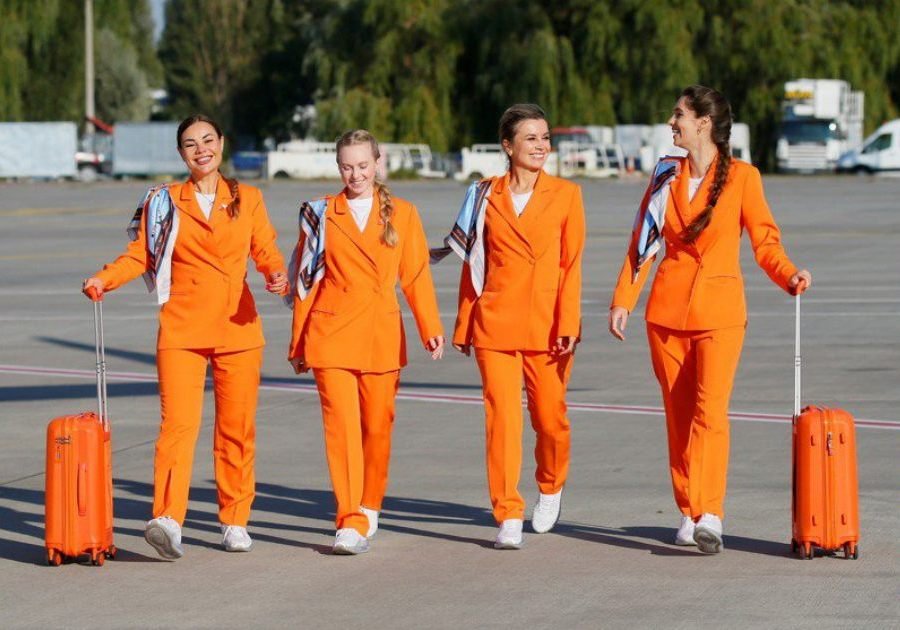 全新的SkyUp女性空服员制服包括NIKE白色运动鞋，以及乌克兰品牌制造的宽松橙色西装外套、长裤和丝巾。 （图取自facebook.com/skyup.aero）