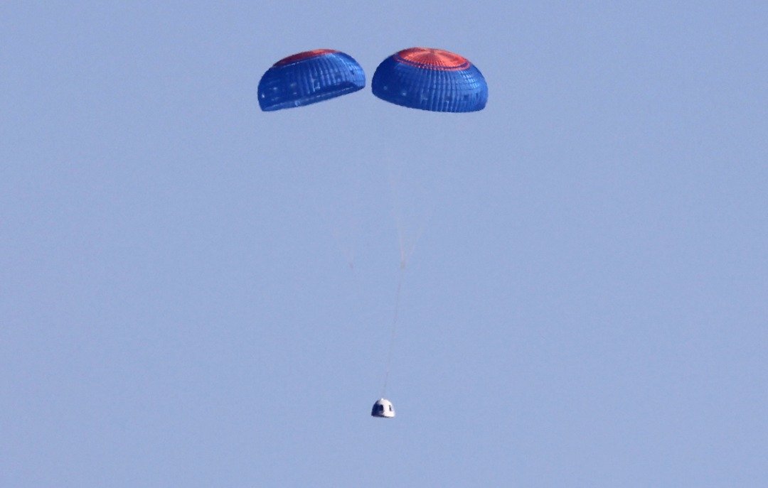 “新谢泼德”号火箭当地时间周三历经约10分钟的太空飞行后，乘员舱透过降落伞，安全降落在美国得克萨斯州沙漠。（图取自法新社/盖蒂图片社）