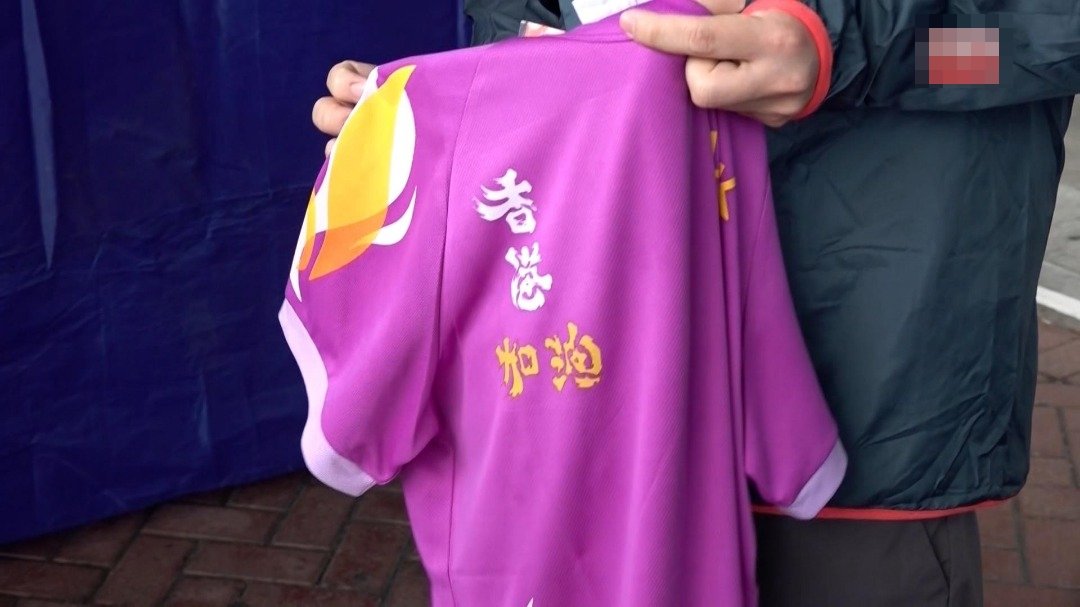 陈先生原本穿上一件紫色、写有“香港加油”字句的上衣，被更换才能参赛。（图取自香港电台）