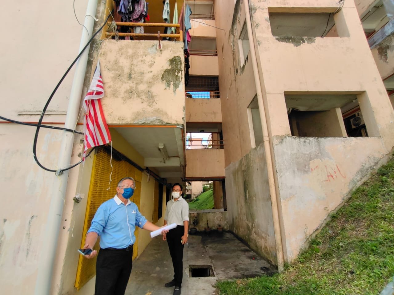 周世扬（左）巡视罗白赤贫组屋，并宣布州政府拨款66万令吉翻新4座组屋。右为吴勇汉。