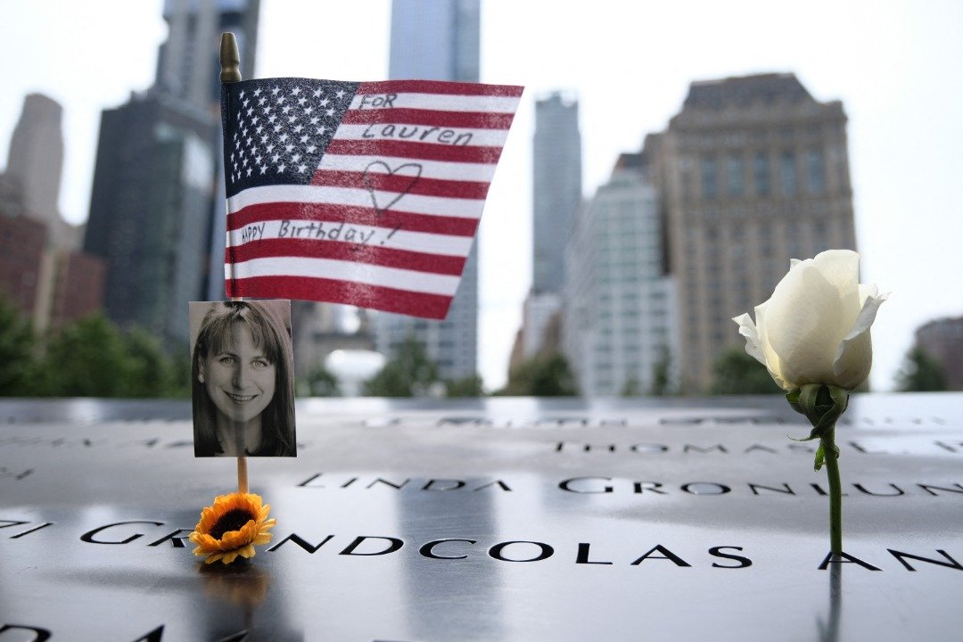 在纽约市归零地（美国世贸中心遗址）的911纪念馆，美国国旗被放置在受害者的名字附近。（图取自法新社）