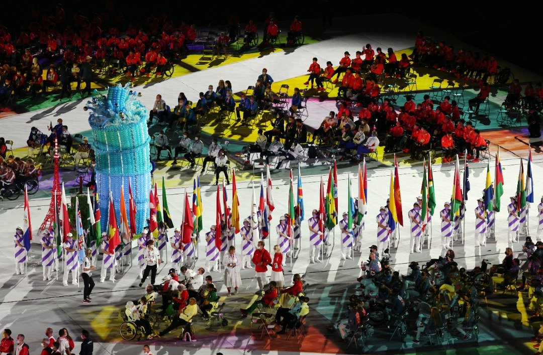 众多志工在残奥会闭幕仪式的游行期间，拿著全球各国和地区的旗帜。（图取自路透社）