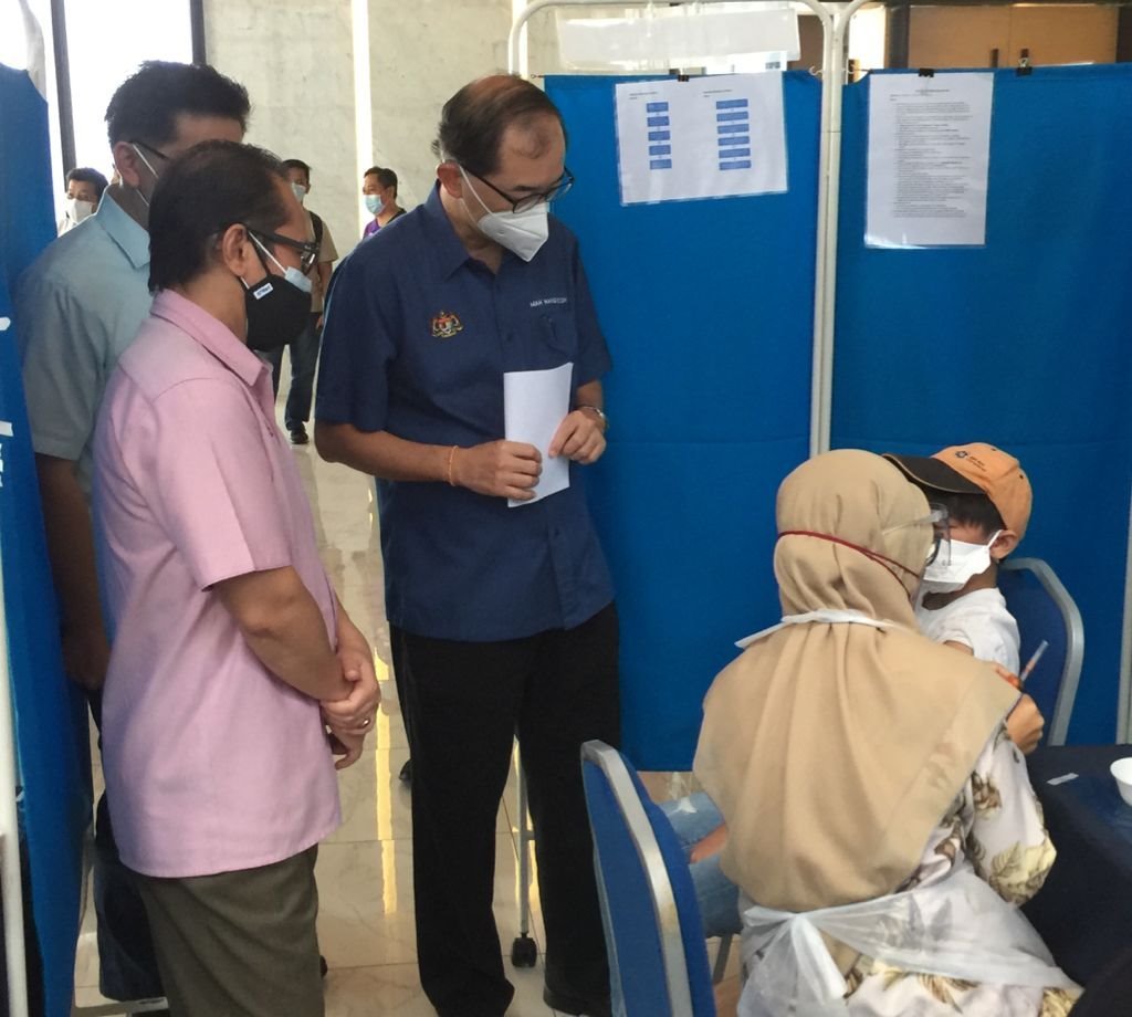 马汉顺（站者右）观察医护人员为学生接种疫苗的过程。