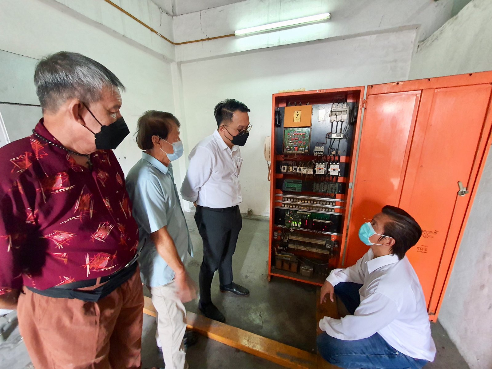 来自通力（Kone）电梯的负责人杨先生（右起），向魏子森等人解释已完成的维修工程。