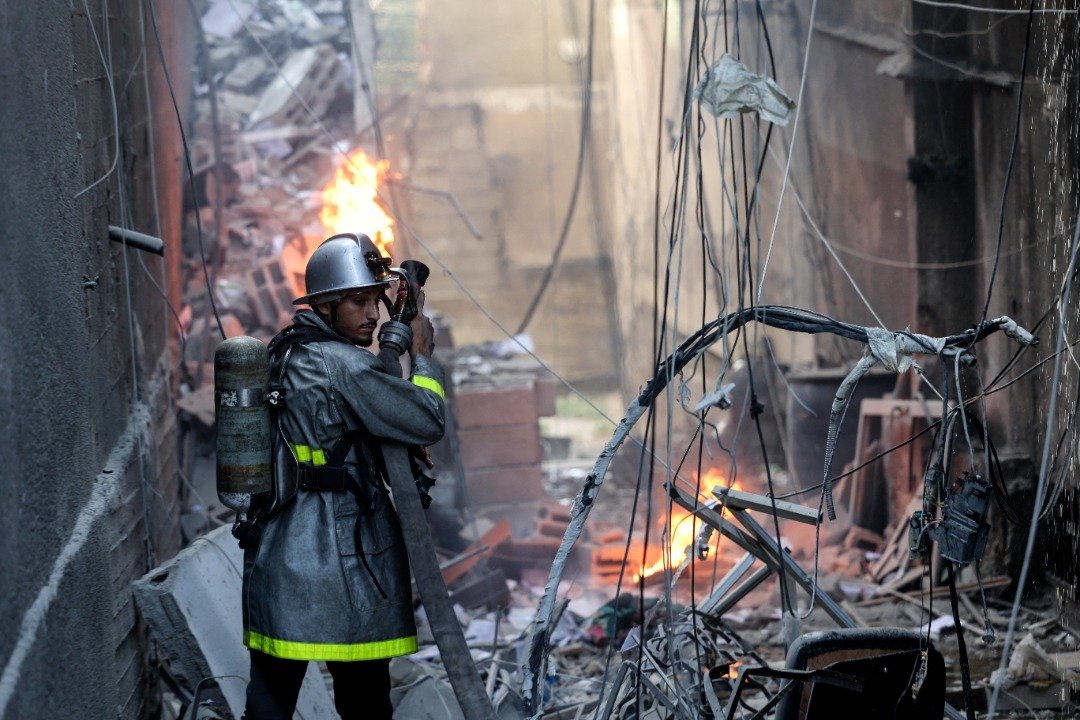 以色列对加沙发动空袭后，消防员在起火燃烧的楼房灌救大火。（图取自法新社）