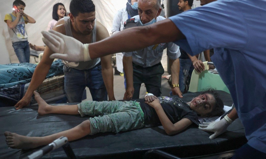 以色列当地时间周六晚在加沙地带南部的拉法发动袭击后，巴勒斯坦医务人员将一名受伤的女孩送往医院。（图取自法新社）
