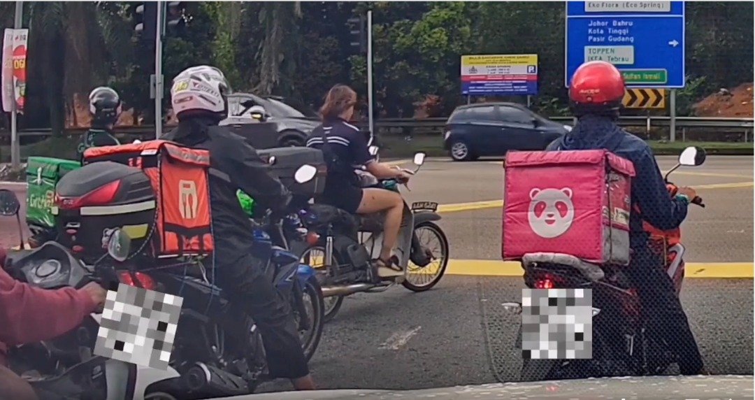 一名在交通前等待通行的女骑士未戴头盔。
