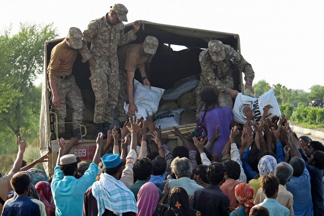 在受灾严重的信德省，士兵们在周日向灾民分发救济食品袋。（图取自法新社）