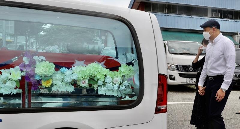 吴宏泽的父母站在灵车后十指紧扣，期间母亲不断拭泪，看者心酸。
