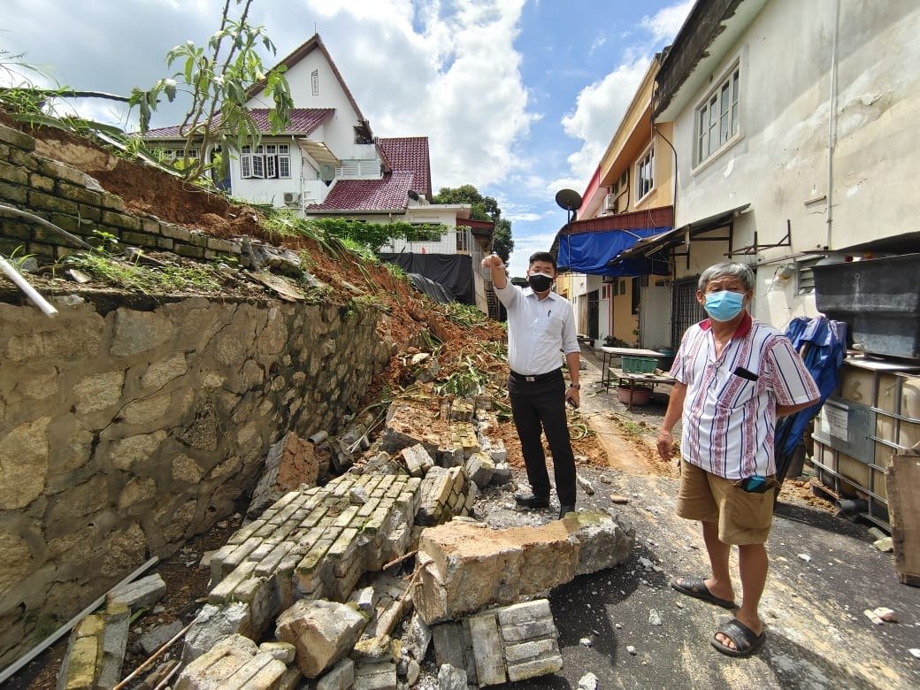 朱建华（左）及王林吉前往巡视土崩及石墙坍塌的情况。