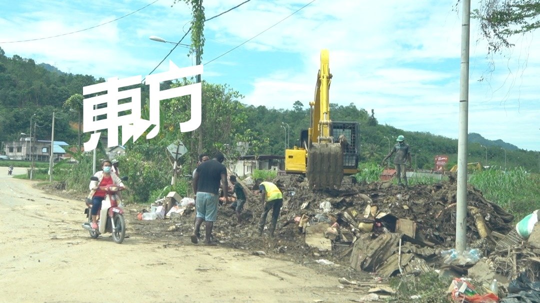 进入双溪都亚新村的入口区，有一个临时垃圾转运站，许多遭浸泡损坏的垃圾，都被丢弃在此，等待清理。