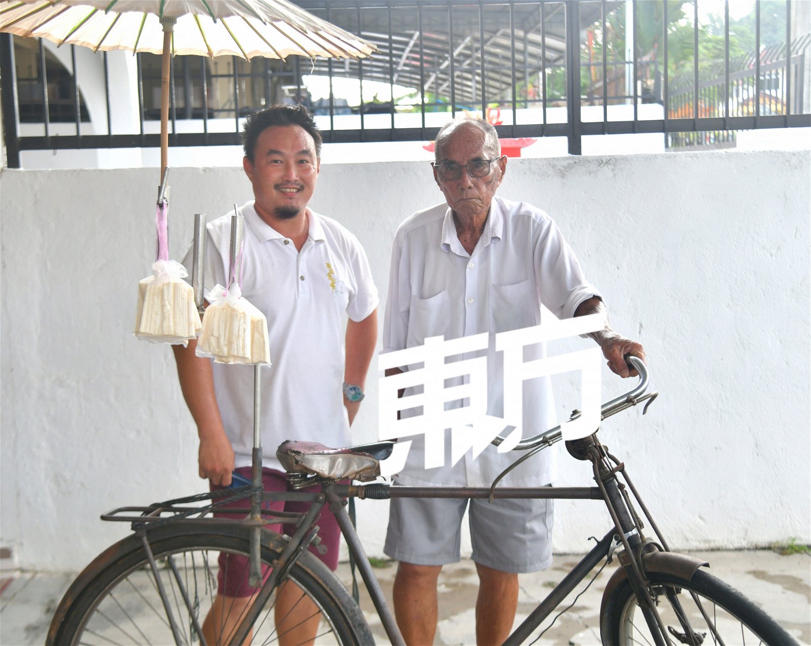 郑艺光（左）说，脚车和纸伞是“芙蓉郑记叮叮糖”的标志。郑金华更说道，当年这辆轿车的售价为90令吉，而且是以分期付款的形式购买，因为50年前90令吉的价值就犹如现在的900令吉。