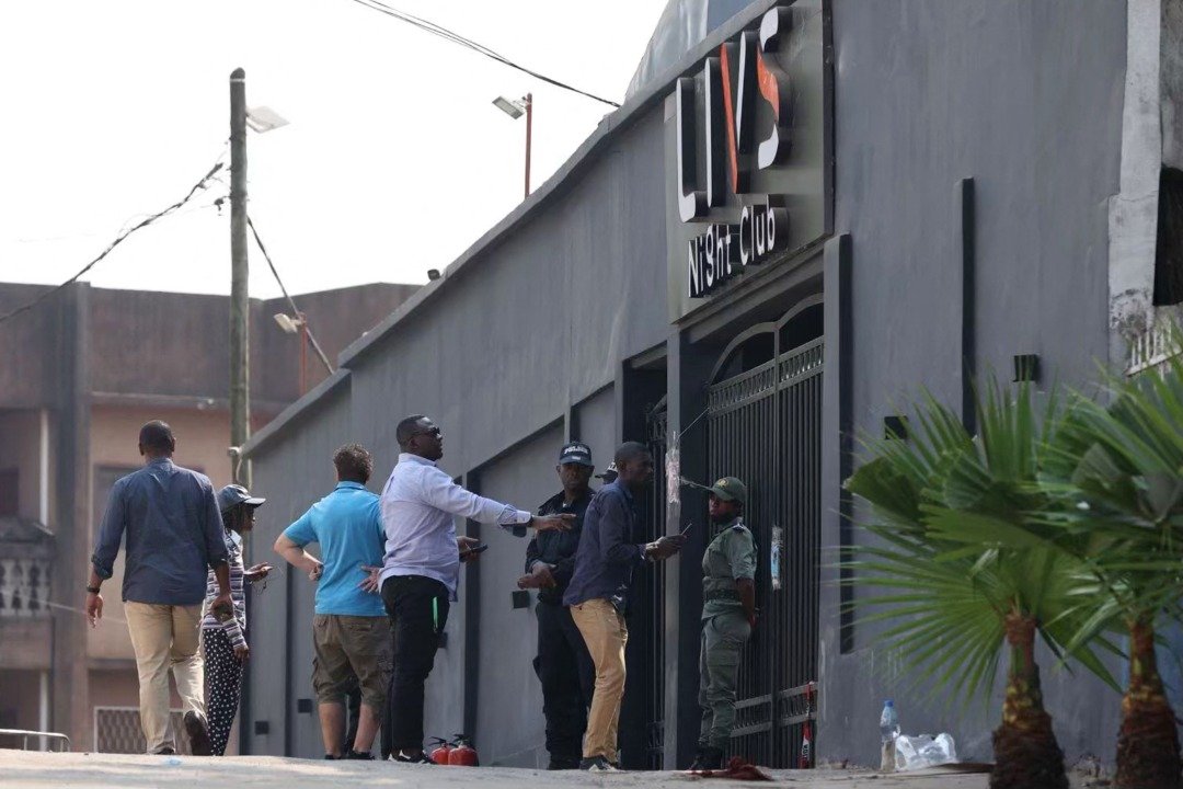 喀麦隆夜总会失火引发爆炸，已夺走至少17条人命，警方持续进行搜救和调查。周日上午警员在该店入口驻守，有人趋前询问内部情况。（图取自法新社）