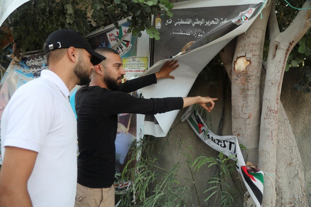 一名巴勒斯坦男子掀开布条，指著导致记者希琳死亡的子弹所留下的弹孔（图取自路透社）