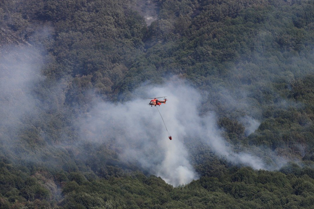 在西班牙Jerte，该国经历了今年的第2次热浪，一架直升机当地时间周日在 Garganta de los Infiernos自然保护区控制山火。（图取自路透社）