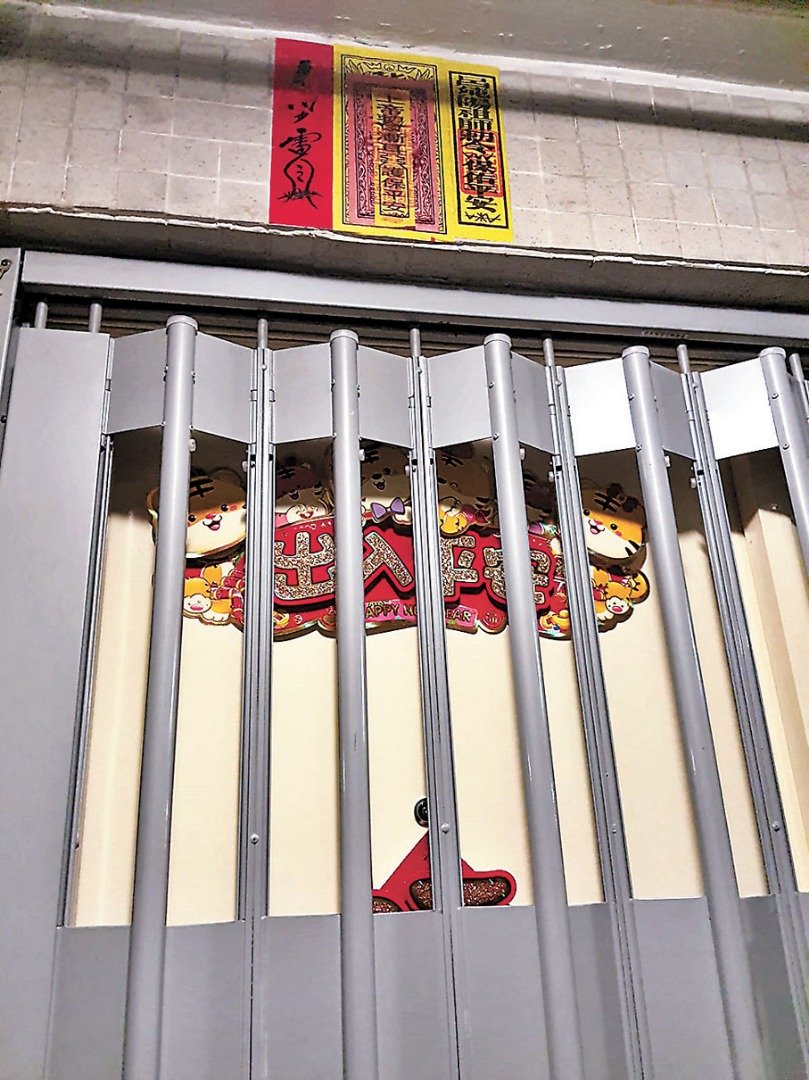 筲箕湾耀东邨耀明楼一个凶宅单位大门上方，贴有多张“镇宅符”以驱散心理阴影。（图取自香港《文汇报》）