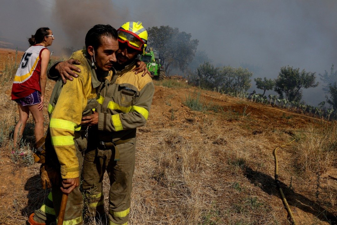 面对烧不尽的山火，在西班牙法拉蒙塔诺斯德塔巴拉参与灭火的一名消防员，看来筋疲力尽，需要同僚搀扶。（图取自路透社）