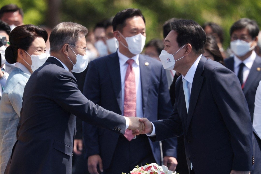 文在寅（左）5月10日出席尹锡悦宣誓就职韩国总统庆典时，双方互相握手。（图取自路透社）