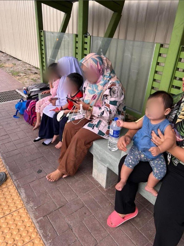 5母子获救，心有馀悸坐在一旁等待救援。