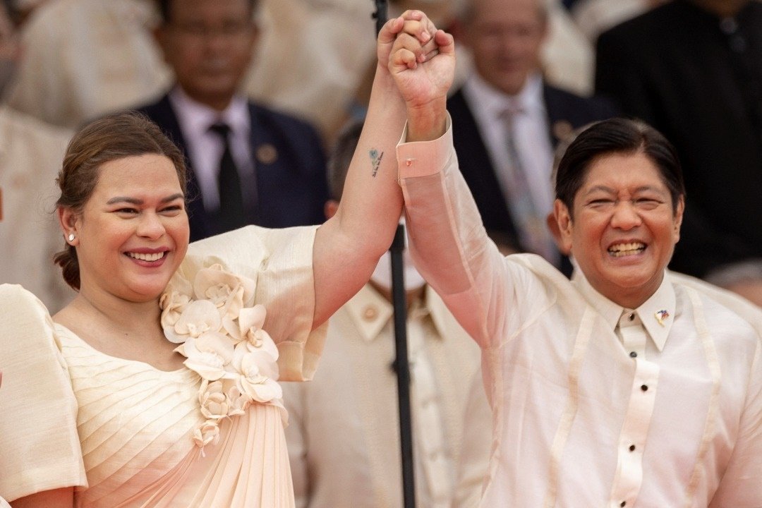 小马科斯（右）和莎拉在菲律宾总统就职礼上笑容满脸地牵手。（图取自路透社）