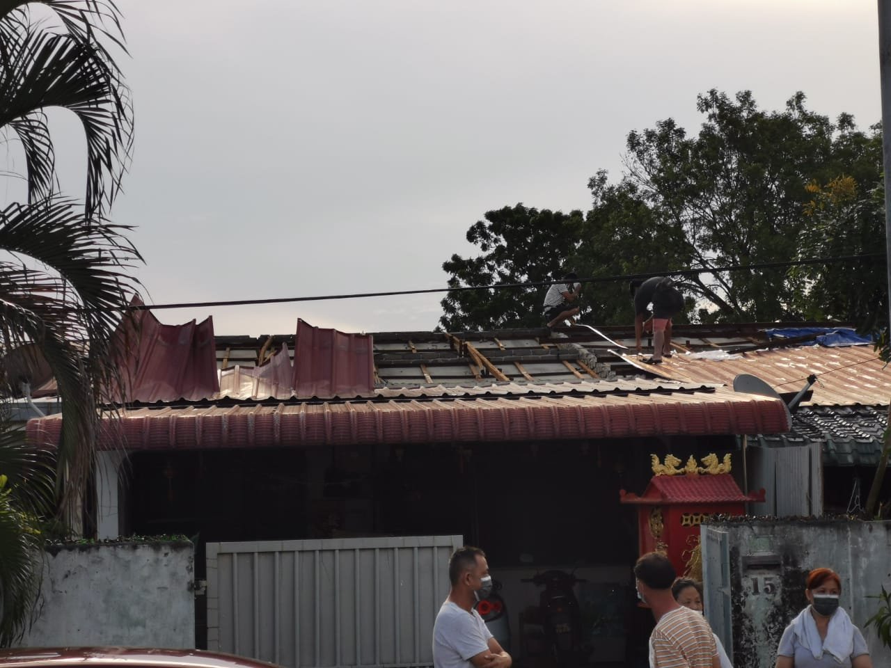 灾民在风灾发生过后，登上屋顶检查损毁情况。