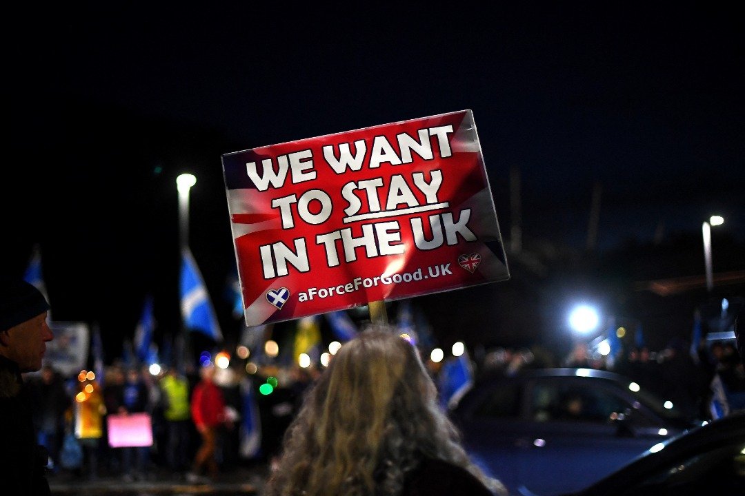 在英国最高法院否决苏格兰独立公投后，反苏格兰独立的支持者聚集在爱丁堡议会外，高举写著：“我们要留在联合王国”的标语。（图取自法新社）
