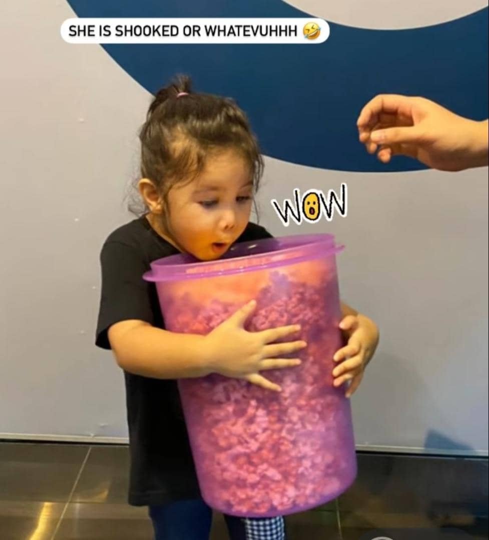 小孩兴奋地抱著一大桶的爆米花。