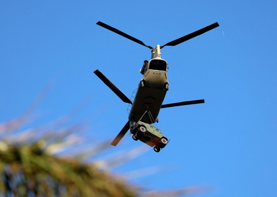 在佛罗里达州迈尔斯堡海滩，一架陆军国民警卫队直升机当地时间周一吊索装载车辆，继续风灾后的援助。（图取自法新社）