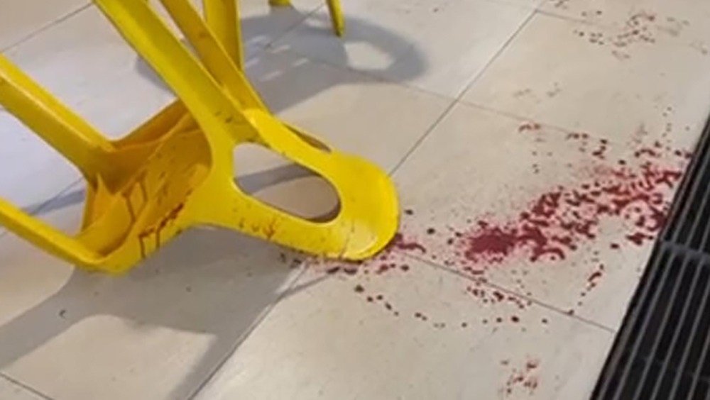 两男子被殴打倒地，地上血迹斑斑，椅子也沾染鲜血。（视频截图）