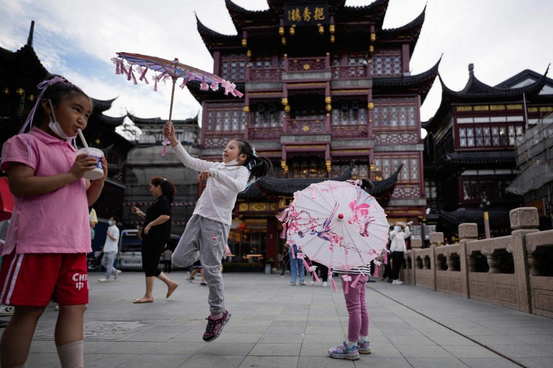 上海豫园商城周五的中秋活动，有小孩拿起精致美丽的纸伞玩乐。（图取自路透社）
