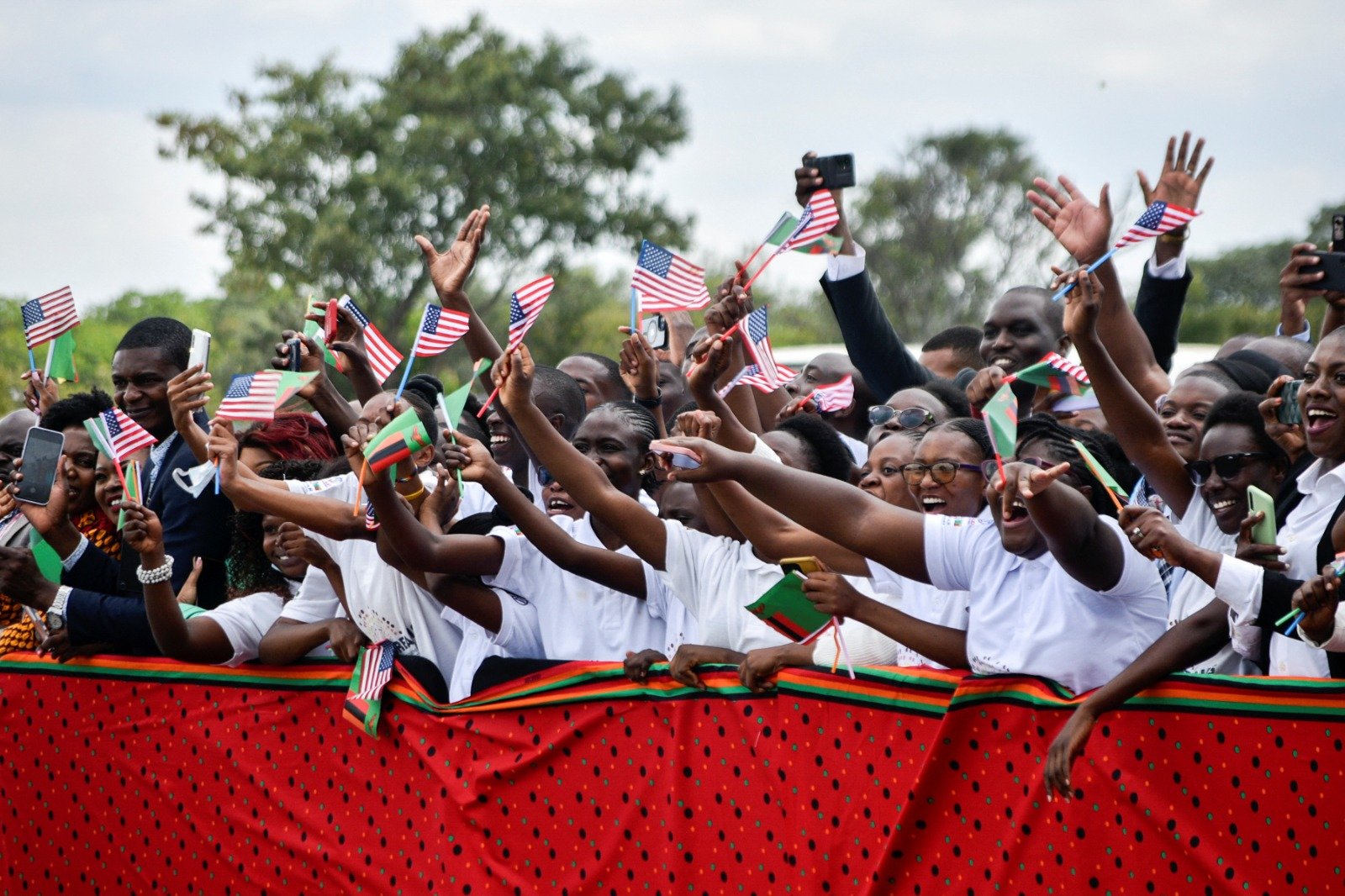 美国副总统哈里斯当地时间周五出访非洲最后一站赞比亚，当地人民聚集在首都卢萨卡挥著美国和赞比亚国旗欢迎哈里斯的到来。（图取自路透社）