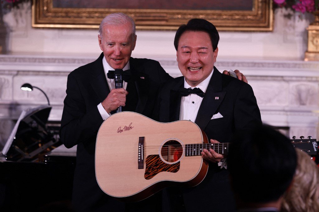韩国总统尹锡悦（左）当地时间周三，在美国华盛顿特区的白宫国宴上，拿著美国总统拜登赠送的、拥有歌手麦克林签名的吉他，即兴演唱麦克林的“美国派”。（图取自盖蒂图片社/法新社）
